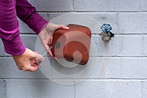 Winterization, womanÃ¢â¬â¢s hands installing foam and plastic faucet cover to prevent pipes freezing photo